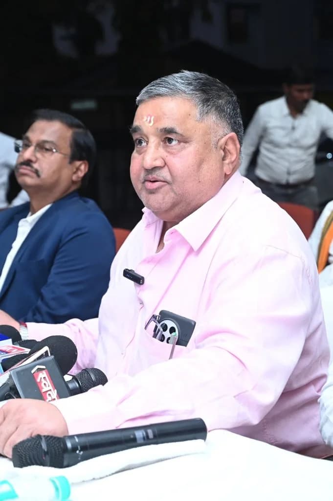 Rajesh Agrawal speaking at a table of microphones